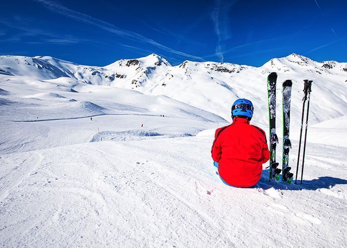 Junge sitzt auf dem Schnee von Livigno mit von Point Rent gemieteter eine Skiausrüstung